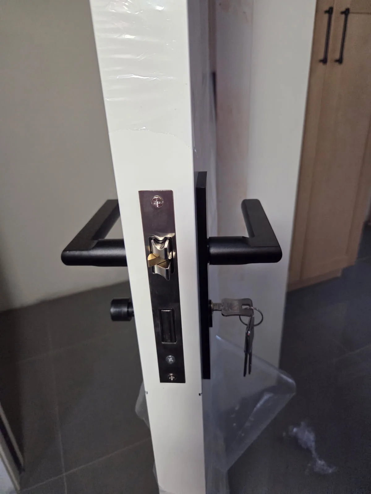 Modern black door hardware and lock installation in progress